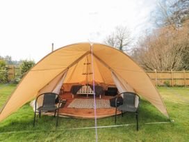 A bell tent with two black chairs outside a bed inside on grass at Bell tent 3 Camerton near Timsbury