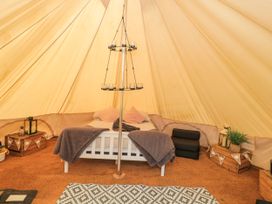 Interior of a bell tent with a bed a candle holder wooden crates and decorative items at Bell tent 3 Camerton near Timsbury