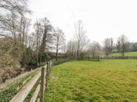A fenced grassy field with trees and a small body of water at Bell tent 3 Camerton near Timsbury