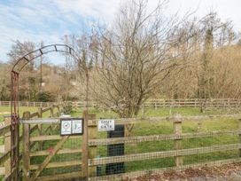 A fenced dog exercise area with wooden gates and metal arch in a grassy outdoor setting at Bell tent 3 Camerton near Timsbury