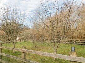 A grassy fenced area with leafless trees and a cloudy sky at Bell tent 3 in Camerton near Timsbury