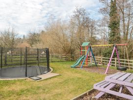 An outdoor play area with a trampoline slide swings and a picnic table at Bell tent 3 Camerton near Timsbury
