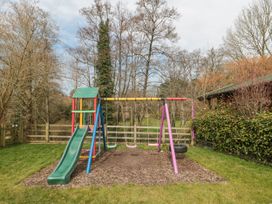 A playground with a slide and swings in a grassy yard at Bell tent 3 Camerton near Timsbury