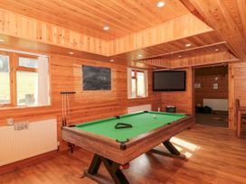 A game room with a pool table a chalkboard a television and wooden walls at Bell tent 3 in Camerton near Timsbury