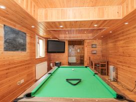 A room with a pool table a mounted television and a small wooden table with chairs at Bell tent 3 in Camerton near Timsbury