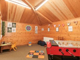 A wooden playroom with a foosball table a tic tac toe mat a small table and chair with toys and posters on the wall at Bell tent 3 Camerton near Timsbury