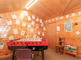 A wooden game room with a foosball table posters and papers on the wall a chair and a bookshelf with books at Bell tent 3 in Camerton near Timsbury