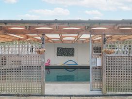 An indoor swimming pool with a wooden lattice fence and roof at Bell tent 3 in Camerton near Timsbury