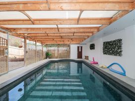 An indoor swimming pool with wooden beam ceiling and lattice fencing at Bell tent 3 Camerton near Timsbury