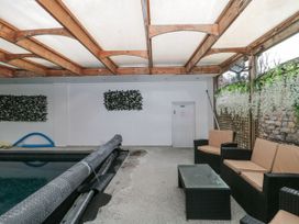 An indoor pool area with wicker seating and a glass table at Bell tent 3 in Camerton near Timsbury