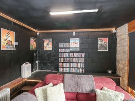 A room with black walls and movie posters above shelves filled with DVDs and a red sofa with cushions in front at Bell tent 3 Camerton near Timsbury