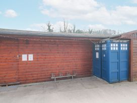A blue police box next to a wooden shed with a bike rack in front at Bell tent 3 in Camerton near Timsbury
