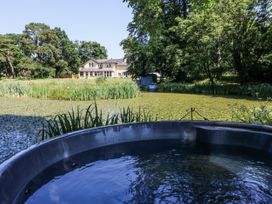 A view of a hot tub and pond with a house in the background at Glanrannell Park House in Llanwrda