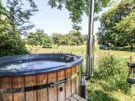 A hot tub near water surrounded by trees at Glanrannell Park House Llanwrda