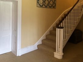 A hallway featuring a staircase and a door at Glanrannell Park House in Crugybar near Brechfa