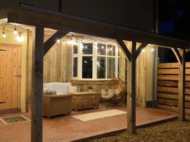A patio with outdoor furniture and hanging lights at Glanrannell Park House Crugybar near Brechfa