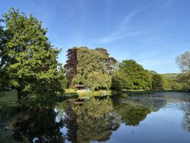 A pond with trees and a shed at Glanrannell Park House Crugybar near Brechfa