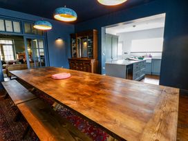 A dining room with a wooden table and bench at The Retreat at Glanrannell Park House, Llansawel