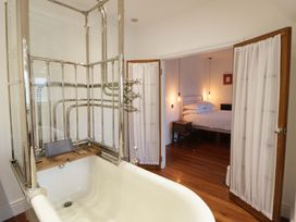 A bathroom with a bathtub and a view of a bedroom at The Retreat at Glanrannell Park House Llansawel