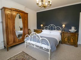 A bedroom with a bed and wardrobe at The Retreat at Glanrannell Park House in Llansawel