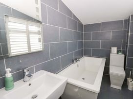 A bathroom with a bath tub and sink at The Retreat at Glanrannell Park House in Llansawel