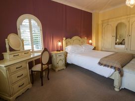 A bedroom with a bed and dresser at The Retreat at Glanrannell Park House Llansawel