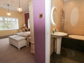 A bedroom with a dressing table and a bathroom area at The Retreat at Glanrannell Park House in Llansawel