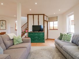 A living room with two sofas a green cabinet tv and a staircase at The Round House in Wardington near Chacombe