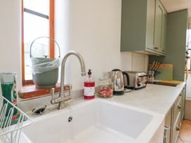 A kitchen countertop with sink, faucet, soap bottle, glass jar, electric kettle, toaster, knives and cutting boards at The Round House in Wardington near Chacombe