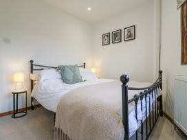 A bedroom with a black metal bed frame white bedding and two bedside tables with lamps at The Round House in Wardington near Chacombe