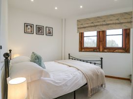 A bedroom with a metal bed frame white bedding lamp on bedside a window with patterned blind and three pictures on wall at The Round House in Wardington near Chacombe