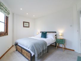 A bedroom with a bed a green bedside table and a framed picture on the wall at The Round House in Wardington near Chacombe