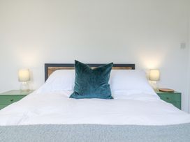 A bedroom with a bed with white bedding and a green pillow with nightstands and lamps on each side at The Round House in Wardington near Chacombe