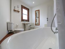 A bathroom with a bathtub toilet sink window and mirror at The Round House in Wardington near Chacombe
