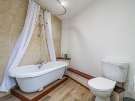 A bathroom with a bathtub with a shower curtain and a toilet at The Round House in Wardington near Chacombe