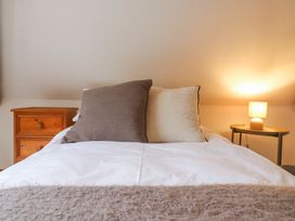 A bed with two pillows a wooden nightstand and a lit lamp on a side table at The Round House in Wardington near Chacombe