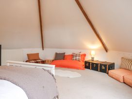 A bedroom with a bed a lamp cushions and storage trunks under a slanted ceiling at The Round House in Wardington near Chacombe