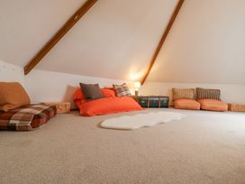 A loft room with cushions arranged against walls under slanted ceiling beams and a small lamp at The Round House in Wardington near Chacombe