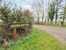 A farm entrance with a sign reading HANGGLAND FARM and a gravel driveway with a wooden gate