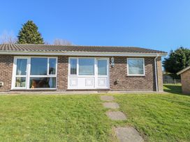 A brick bungalow with white doors and windows and a grass lawn in front at Lighthouse View in Winterton-On-Sea