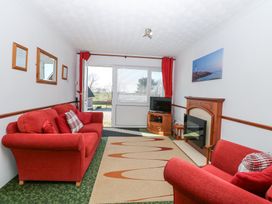 A living room with red sofas a fireplace a television and a door with windows at Lighthouse View in Winterton-On-Sea