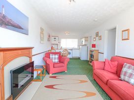 A living room and kitchen area with red sofa and armchair and dining table at Lighthouse View in Winterton-On-Sea