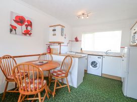 A kitchen with a round wooden table and four chairs a washing machine and a refrigerator at Lighthouse View in Winterton-On-Sea