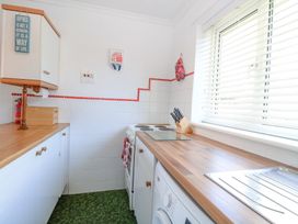 A small kitchen with wooden countertops a stove and a washing machine at Lighthouse View in Winterton-On-Sea