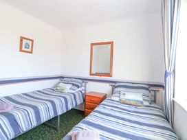 A bedroom with two single beds with striped bedding a wooden nightstand in between and a mirror on the wall at Lighthouse View Winterton-On-Sea