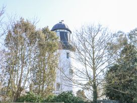 A lighthouse partially obscured by trees and bushes at Lighthouse View in Winterton-On-Sea