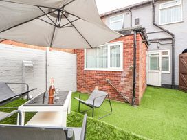 An outdoor patio area with chairs table umbrella and a bottle of wine at Anfield Stadium Short Stay and Free Parking in Liverpool