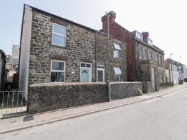 A street view of stone houses with a low stone wall and a lamppost in front at Colliers Cottage in Cinderford