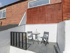 A small outdoor patio with two chairs and a round table with a bottle and two glasses at Colliers Cottage in Cinderford