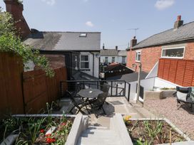 A backyard patio area with a table and chairs surrounded by flower beds and gravel at Colliers Cottage in Cinderford